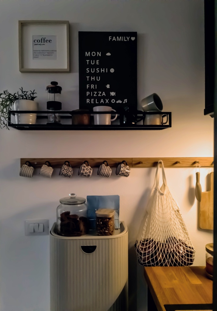 Mensola per angolo caffè con tazze appese, barattoli e decorazioni murali.