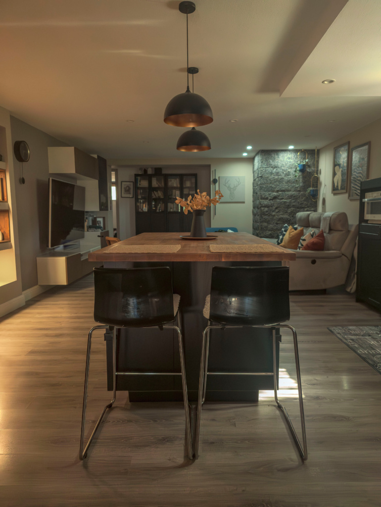 Open space moderno con cucina nera e isola in legno massiccio